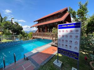 un cartel junto a una piscina frente a una casa en Red House the Garden Stay in Bukit Tinggi by PLAY, en Bentong