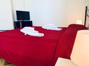 twee opvouwbare handdoeken bovenop een rood bed bij Villa Nonno Alfonso in Marina di Camerota