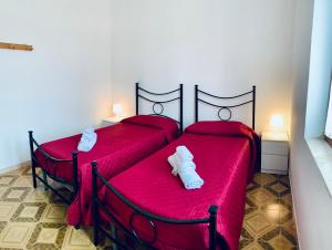 twee bedden in een kamer met rode lakens en witte schoenen bij Villa Nonno Alfonso in Marina di Camerota