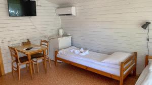 a small room with a bed and a table and a tv at Olle Holiday house in Ventspils +5 photos