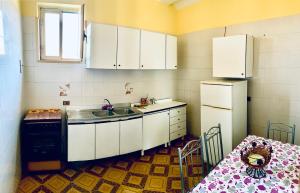 een keuken met witte kasten, een wastafel en een tafel bij Villa Nonno Alfonso in Marina di Camerota
