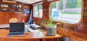 a laptop computer sitting on a wooden table with a plant at Péniche Sir Lancelot in Thuin