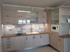 eine Küche mit weißen Schränken und einem Waschbecken in der Unterkunft Wildflower Apartment in Balatonfüred