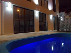 a swimming pool in front of a house at night at Hotel Refugio in Maceió