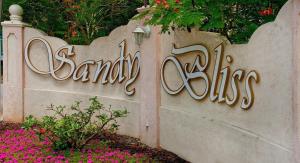 a sign for a santa ana sign with pink flowers at Sandy Bliss Condominiums in Saint James