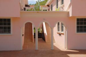an entrance to a pink building with an archway at Sandy Bliss Condominiums in Saint James