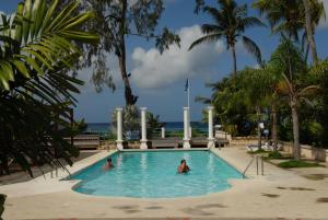 two people in a swimming pool with palm trees at Sandy Bliss Condominiums in Saint James