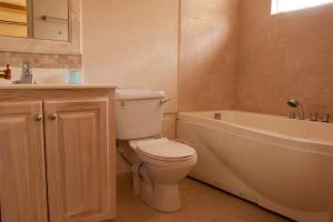 a bathroom with a toilet and a tub and a sink at Sandy Bliss Condominiums in Saint James
