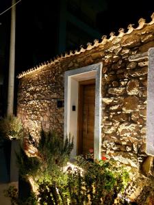 a stone building with a wooden door and flowers at Boutique Athensairport Apartments in Markopoulo