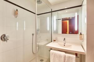 La salle de bains blanche est pourvue d'un lavabo et d'une douche. dans l'établissement B&B HOTEL Saint-Quentin-en-Yvelines Centre Gare 4 étoiles, à Montigny-le-Bretonneux