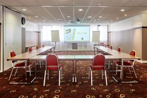 a conference room with tables and chairs and a projection screen at B&B HOTEL Saint-Quentin-en-Yvelines Centre Gare 4 étoiles in Montigny-le-Bretonneux