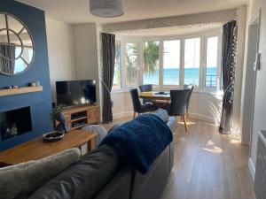 a living room with a couch and a table at WORTHING BEACH 180 - 2 bed seafront apartment with private parking in Worthing