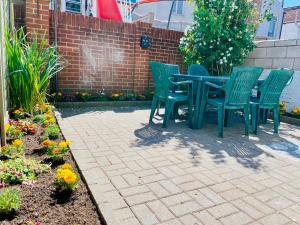 un tavolo verde e sedie su un patio fiorito di Clive Crest house a Portsmouth