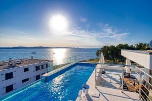 a swimming pool on top of a building next to the water at Crystal Holiday Residence in Sukošan