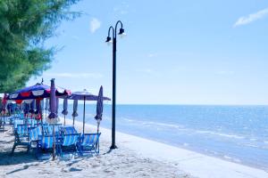 a group of chairs and umbrellas on a beach at GOLDEN GUESTHOUSE by The Beach Cha Am in Cha Am