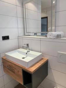 ein Badezimmer mit einem weißen Waschbecken und einem Spiegel in der Unterkunft Clubhotel Götzens in Innsbruck