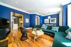 a living room with blue walls and a green couch at NEW Elegant 2BD Flat Maida Vale Central London in London