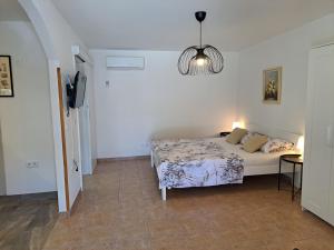 a white bedroom with a bed and a lamp at Apartments Dandić in Orlec