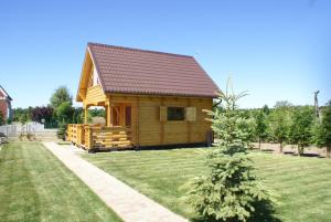 una pequeña cabaña de madera con un árbol en el patio en Domek Morski 2C, en Łukęcin 4 fotos más
