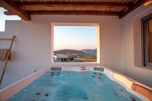a jacuzzi tub in a room with a window at Katikies Ftelia Mykonos in Panormos Mykonos