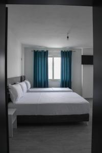 a bedroom with a large bed with blue curtains at LUMNIK - Hotel & Apartments in Lezhë