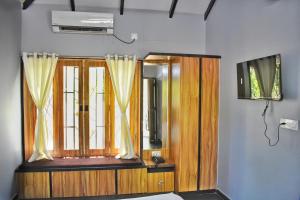 a room with a television and a window with curtains at Raghunandan Resort in Nashik