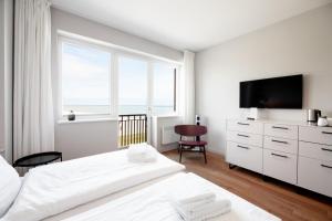 a white bedroom with a large window and a television at Bades Huk Marina Hotel in Hohen Wieschendorf