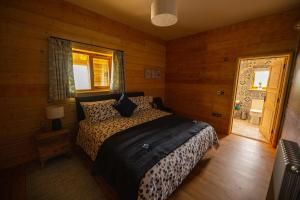 ein Schlafzimmer mit einem Bett in einem Zimmer mit Holzwänden in der Unterkunft Luxury Log Cabin with a Hot Tub in Stone