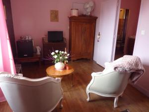 a living room with two chairs and a table with flowers at Maison d'Hôtes Les Belles de Mai in Pontorson