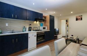 a kitchen with dark blue cabinets and a table with chairs at Apartment Besima 2178 in Pula +7 photos