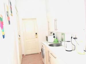 a white kitchen with a sink and a microwave at City Rooms in Budapest +22 photos