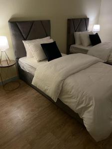 1 dormitorio con 2 camas con sábanas y almohadas blancas en شقق مفروشه خاصه بالطائف, en Taif