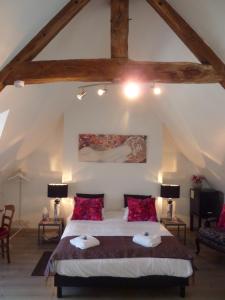 a bedroom with a large bed with red pillows at Maison d'Hôtes Les Belles de Mai in Pontorson