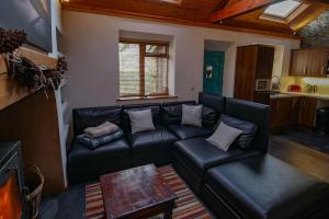 ein Wohnzimmer mit einem schwarzen Ledersofa in der Unterkunft Beili Glas Cottage in Pontardawe + 16 Fotos