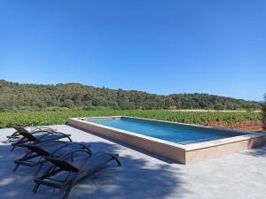 uma piscina com duas cadeiras e uma piscina em Sous Les Pins gîtes et chambres d'hôtes em La Londe-les-Maures