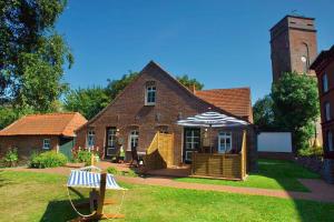 a large brick house with an umbrella in the yard at Leuchtturmhaus 1888 EG Wohnung in Borkum