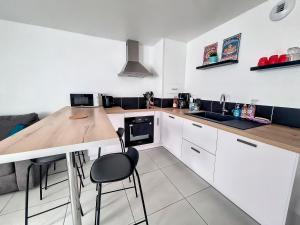 kuchnia z białymi szafkami i drewnianym blatem w obiekcie Chez Ellie-Maison de ville à Concarneau w mieście Concarneau