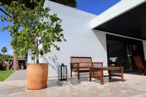 two benches and a tree in front of a building at Villa del Fresno in Chiclana de la Frontera