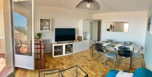 a living room with a television and a table and chairs at CAP SUD 83 APPART VUE MER 200m plages in Hyères