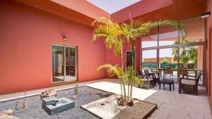 a living room with red walls and palm trees at Villa Vulcano by Calima Villas in Costa de Antigua