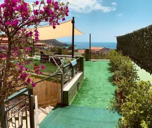 een tuin met groen gras en paarse bloemen en een hek bij Villa Nonno Alfonso in Marina di Camerota
