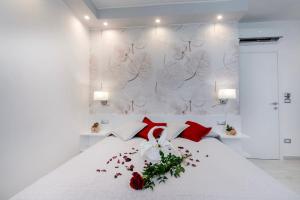un letto bianco con cuscini rossi e fiori di Profumo di Mare Offre Parcheggio Gratuito a Maiori