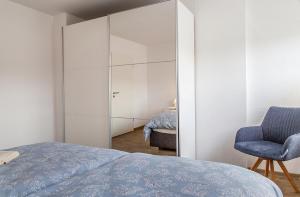 ein Schlafzimmer mit einem Spiegel, einem Bett und einem Stuhl in der Unterkunft 50137 "Deichkajüte 6" in Carolinensiel