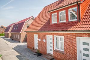 eine Reihe von Backsteinhäusern mit roten Dächern in der Unterkunft 50137 "Deichkajüte 6" in Carolinensiel