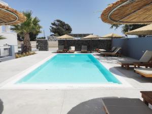 una piscina con sedie e ombrelloni in un resort di White Lily Santorini - Adults Only 16 Plus a Perivolos