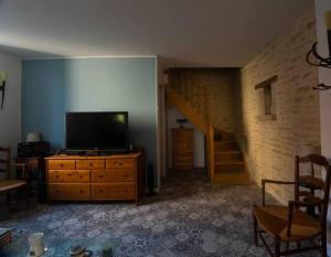 ein Wohnzimmer mit einem TV und einer Treppe in der Unterkunft Au Pont Vert in Fontaine-Française