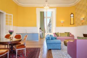 uma sala de estar com paredes amarelas e uma mesa e cadeiras em Residentas Arco do Bandeira em Lisboa