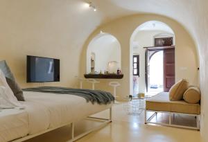 a bedroom with a large bed and a tv at Azalea Houses Cave Villa in Oia