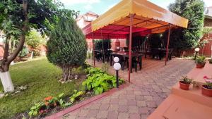 a pavilion with a table and chairs in a garden at Vila Tropical in Costinesti