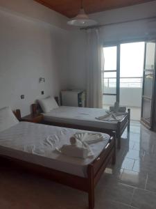 two beds in a room with a large window at Tarra in Agia Roumeli